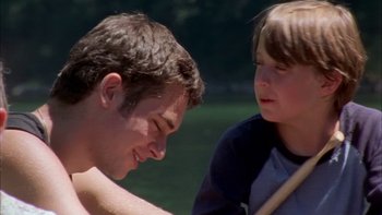 Movie still from “Mean Creek” (2004), directed by Jacob Estes – A man and a boy are sitting in the grass; Medium shot, Over the shoulder angle