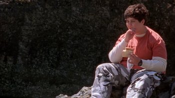 Movie still from “Mean Creek” (2004), directed by Jacob Estes – A boy sitting on the ground eating a sandwich; Medium shot, High angle