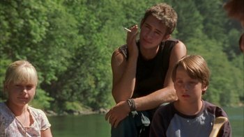 Two young men sitting next to a body of water