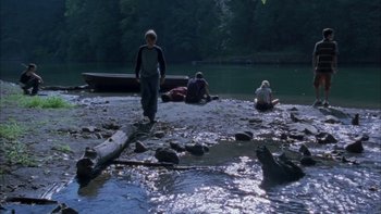 Movie still from “Mean Creek” (2004), directed by Jacob Estes – A group of people sitting and standing on the shore of a lake; Wide shot, High angle