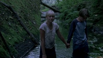 Movie still from “Mean Creek” (2004), directed by Jacob Estes – A young girl and a young boy holding hands while standing in a stream; Medium shot, High angle