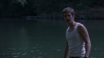 Movie still from “Mean Creek” (2004), directed by Jacob Estes – A man standing in front of a body of water; Medium shot, Low angle