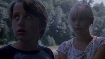 Movie still from “Mean Creek” (2004), directed by Jacob Estes – Two young people standing next to each other in front of trees; Close Up shot, Low angle