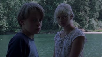 Movie still from “Mean Creek” (2004), directed by Jacob Estes – Two young people standing next to each other near a body of water; Medium shot, Low angle