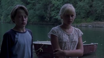 Movie still from “Mean Creek” (2004), directed by Jacob Estes – Two young people standing next to each other near a body of water; Medium shot, Low angle