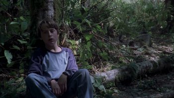 Movie still from “Mean Creek” (2004), directed by Jacob Estes – A young boy sitting in the woods next to a tree; Medium shot, High angle