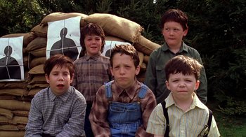 Movie still from “Mean Girls” (2004), directed by Mark Waters – A group of young boys sitting next to each other in front of hay bales; Medium shot, Low angle