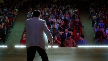 Movie still from “Mean Girls” (2004), directed by Mark Waters – A man standing in front of a crowd of people in front of an audience; Extreme Wide shot, High angle