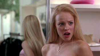 Movie still from “Mean Girls” (2004), directed by Mark Waters – A young woman looking in the mirror in front of a mirror; Close Up shot, Over the shoulder angle