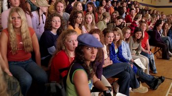 Movie still from “Mean Girls” (2004), directed by Mark Waters – A group of people sitting in a room watching something; Wide shot, High angle