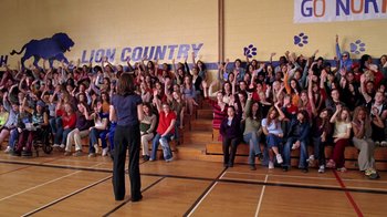 Movie still from “Mean Girls” (2004), directed by Mark Waters – A group of people sitting in front of an audience in a gym; Extreme Wide shot, High angle