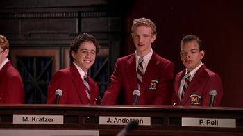 Movie still from “Mean Girls” (2004), directed by Mark Waters – A group of young men standing next to each other in front of microphones; Medium shot, Low angle