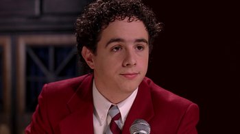 Movie still from “Mean Girls” (2004), directed by Mark Waters – A man in a red jacket and a microphone; Close Up shot, Low angle