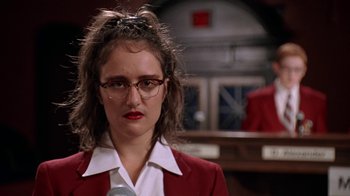 Movie still from “Mean Girls” (2004), directed by Mark Waters – A woman in glasses and a red jacket is standing in front of a counter; Close Up shot, Low angle
