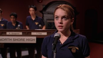 Movie still from “Mean Girls” (2004), directed by Mark Waters – A girl in a uniform is speaking into a microphone; Medium shot, Over the shoulder angle