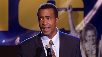 Movie still from “Mean Girls” (2004), directed by Mark Waters – A person speaking on a microphone; Close Up shot, High angle