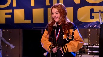 Movie still from “Mean Girls” (2004), directed by Mark Waters – A woman standing in front of a microphone on a stage; Medium shot, Over the shoulder angle