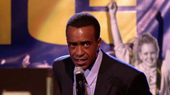 Movie still from “Mean Girls” (2004), directed by Mark Waters – A man in a suit and tie holding a microphone; Close Up shot, Low angle