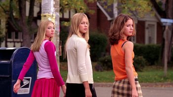 Movie still from “Mean Girls” (2004), directed by Mark Waters – Three young women standing next to each other on a sidewalk; Medium shot, Low angle