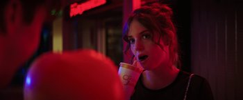 Movie still from “Fear Street: Part One - 1994” (2021), directed by Leigh Janiak – A woman is drinking a drink in a dark room; Close Up shot, Over the shoulder angle