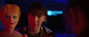 Movie still from “Fear Street: Part One - 1994” (2021), directed by Leigh Janiak – A young man is smiling for the camera in the dark; Close Up shot, Low angle