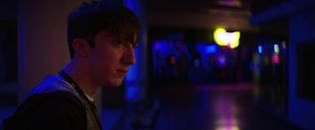 Movie still from “Fear Street: Part One - 1994” (2021), directed by Leigh Janiak – A young man is standing in a dark room; Close Up shot, Over the shoulder angle