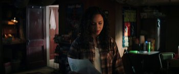 Movie still from “Fear Street: Part One - 1994” (2021), directed by Leigh Janiak – A woman in plaid shirt looking down at a piece of paper; Medium shot, Over the shoulder angle