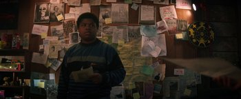 Movie still from “Fear Street: Part One - 1994” (2021), directed by Leigh Janiak – A man standing in front of a wall covered with papers; Medium shot, High angle