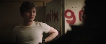 Movie still from “Fear Street: Part One - 1994” (2021), directed by Leigh Janiak – A man standing in front of a wall with graffiti on it; Medium shot, Over the shoulder angle