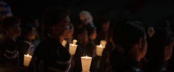 Movie still from “Fear Street: Part One - 1994” (2021), directed by Leigh Janiak – A group of people standing next to lit candles in the dark; Close Up shot, Over the shoulder angle