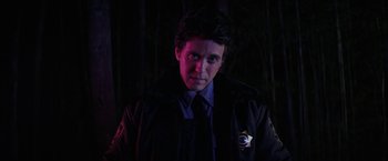 Movie still from “Fear Street: Part One - 1994” (2021), directed by Leigh Janiak – A man in a police uniform standing in the dark; Close Up shot, Over the shoulder angle