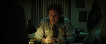 Movie still from “Fear Street: Part One - 1994” (2021), directed by Leigh Janiak – A man sitting at a table in a police station; Close Up shot, Over the shoulder angle