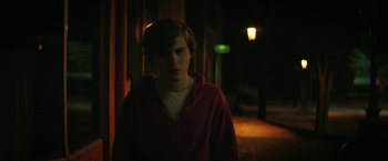 Movie still from “Fear Street: Part One - 1994” (2021), directed by Leigh Janiak – A young man standing in the dark in front of a street light; Medium shot, Over the shoulder angle