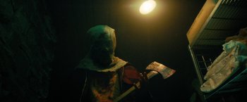 Movie still from “Fear Street: Part One - 1994” (2021), directed by Leigh Janiak – A person in a costume holding an axe in the dark; Close Up shot, Low angle