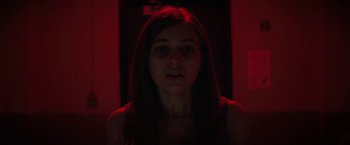 Movie still from “Fear Street: Part One - 1994” (2021), directed by Leigh Janiak – A woman with long brown hair standing in a dark room; Close Up shot, Low angle
