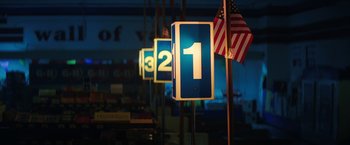 Movie still from “Fear Street: Part One - 1994” (2021), directed by Leigh Janiak – A row of street signs in a room with american flags on poles; Extreme Close Up shot, Low angle