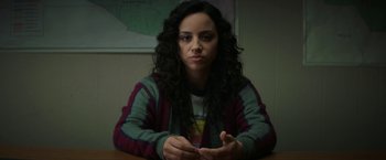Movie still from “Fear Street: Part One - 1994” (2021), directed by Leigh Janiak – A woman sitting at a table in front of a map; Close Up shot, Over the shoulder angle
