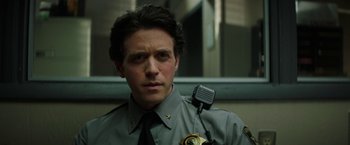 Movie still from “Fear Street: Part One - 1994” (2021), directed by Leigh Janiak – A man in a police uniform is looking at the camera; Close Up shot, Low angle