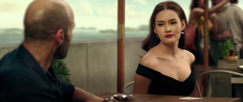 Movie still from “Mechanic: Resurrection” (2016), directed by Dennis Gansel – A woman sitting at a table with a cigarette in her mouth; Medium shot, Over the shoulder angle