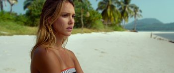 Movie still from “Mechanic: Resurrection” (2016), directed by Dennis Gansel – A beautiful young woman standing on top of a sandy beach; Close Up shot, Over the shoulder angle