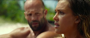 Movie still from “Mechanic: Resurrection” (2016), directed by Dennis Gansel – A man and a woman are sitting in the sand; Close Up shot, Over the shoulder angle