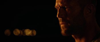 Movie still from “Mechanic: Resurrection” (2016), directed by Dennis Gansel – A man's face in the dark; Close Up shot, Over the shoulder angle