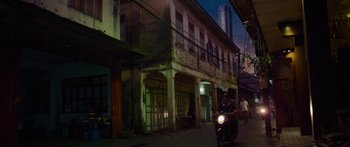 Movie still from “Mechanic: Resurrection” (2016), directed by Dennis Gansel – A man riding a motorcycle down a street at night; Extreme Wide shot, Low angle
