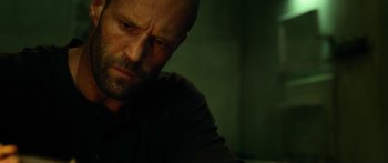 Movie still from “Mechanic: Resurrection” (2016), directed by Dennis Gansel – A man with a beard is sitting down; Close Up shot, Low angle