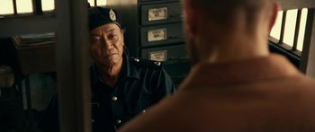 Movie still from “Mechanic: Resurrection” (2016), directed by Dennis Gansel – A man in a police uniform looking into a mirror; Close Up shot, Over the shoulder angle