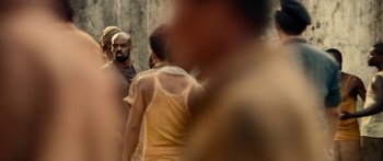 Movie still from “Mechanic: Resurrection” (2016), directed by Dennis Gansel – A group of people standing around in a room; Medium shot, Over the shoulder angle