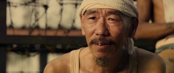 Movie still from “Mechanic: Resurrection” (2016), directed by Dennis Gansel – An older man with a bandage on his head; Close Up shot, Low angle