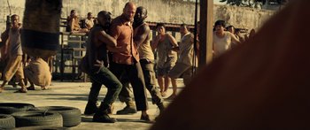 Movie still from “Mechanic: Resurrection” (2016), directed by Dennis Gansel – A group of men are dancing in a street; Wide shot, Over the shoulder angle