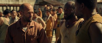 Movie still from “Mechanic: Resurrection” (2016), directed by Dennis Gansel – A couple of men standing next to each other on a street; Medium shot, Over the shoulder angle