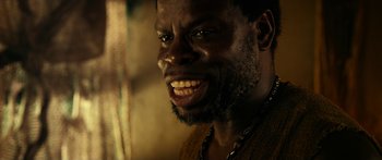 Movie still from “Mechanic: Resurrection” (2016), directed by Dennis Gansel – A person with a beard smiling; Close Up shot, Low angle